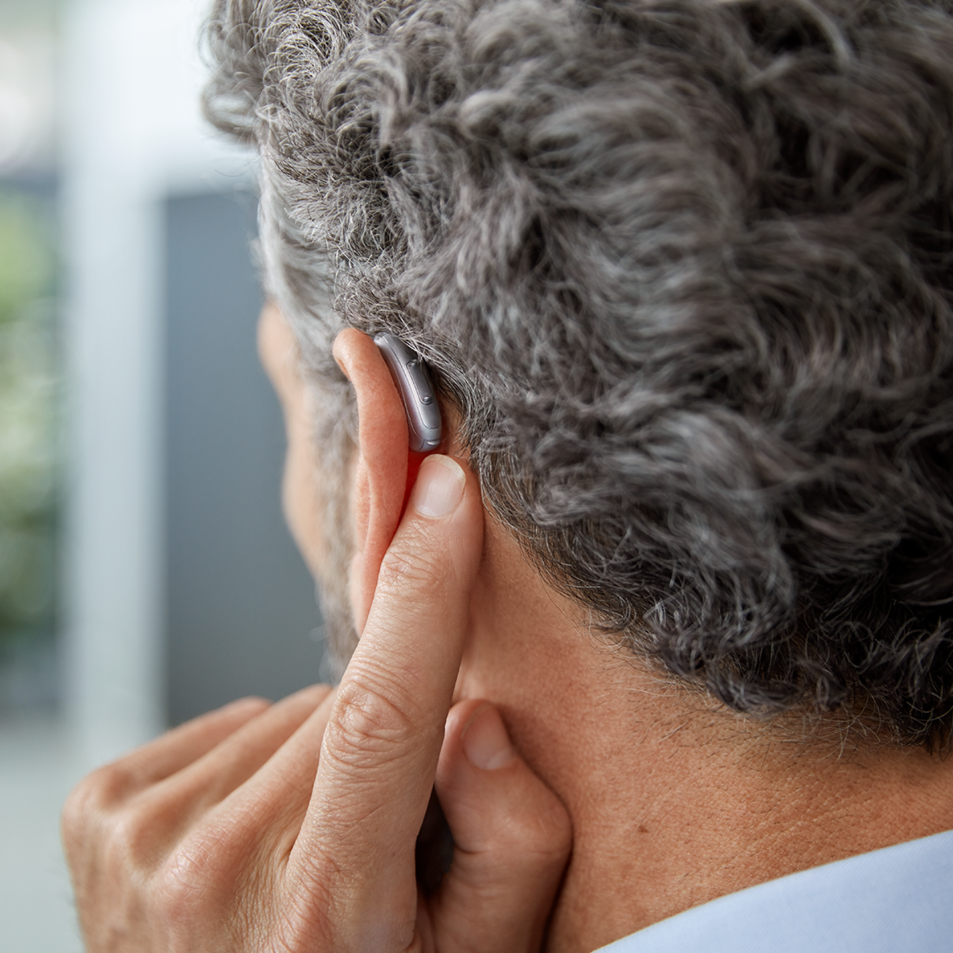 Mann zeigt auf sein Signia Hinter dem Ohr Hörsystem